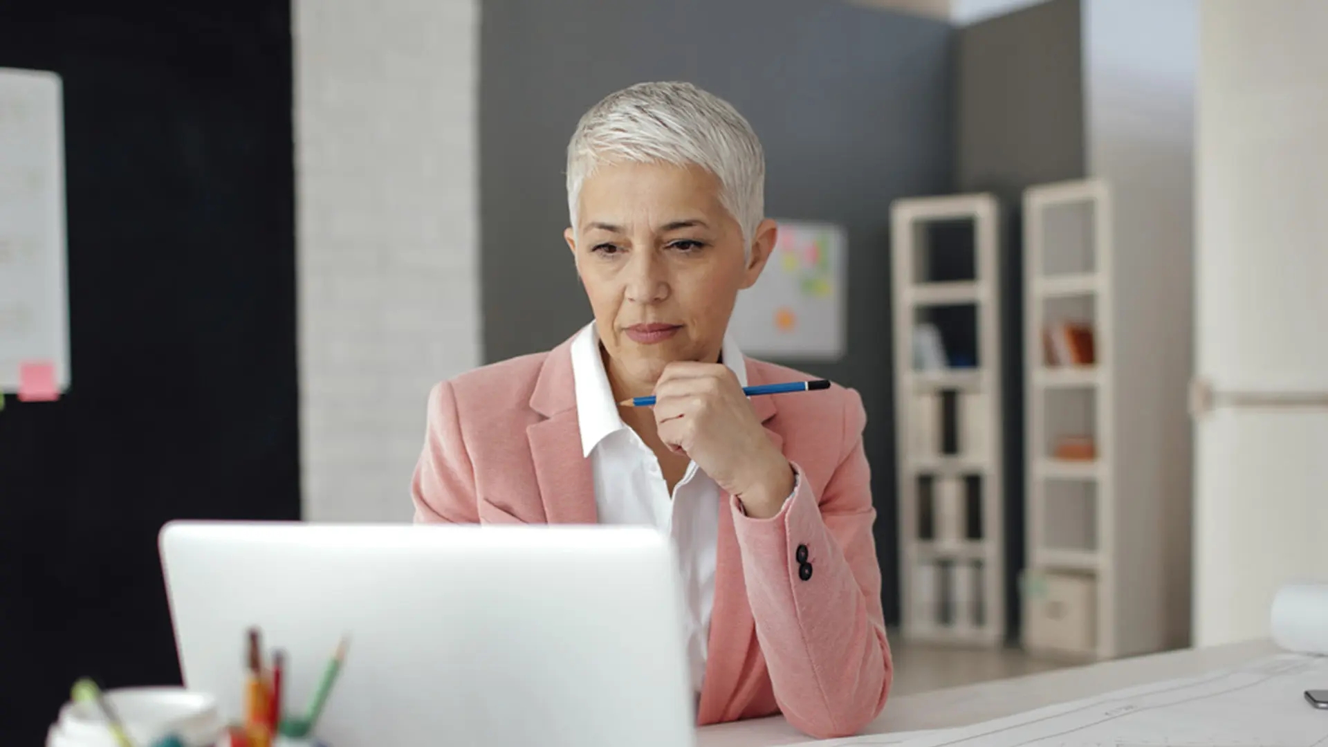 Woman at office working on laptop and analyzing data